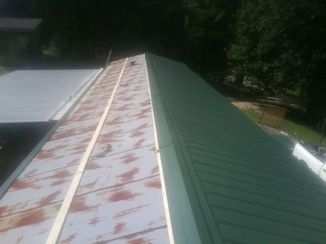 Old rusted panels beside newly installed green metal roofing — Wind Damage Roof Repair by Roofing Brothers in Camdenton
