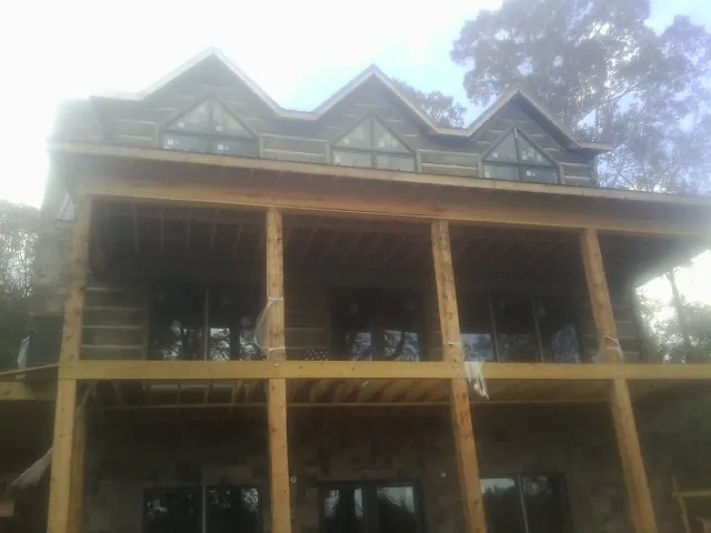 Dormers and porch framing on a large log home under construction — Roof Coating work by our crew in Camdenton
