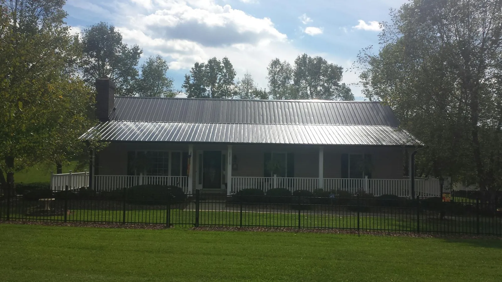 Gray metal roof on a brick ranch with a full width front porch — Gutter Guard Installation work by our crew in Camdenton