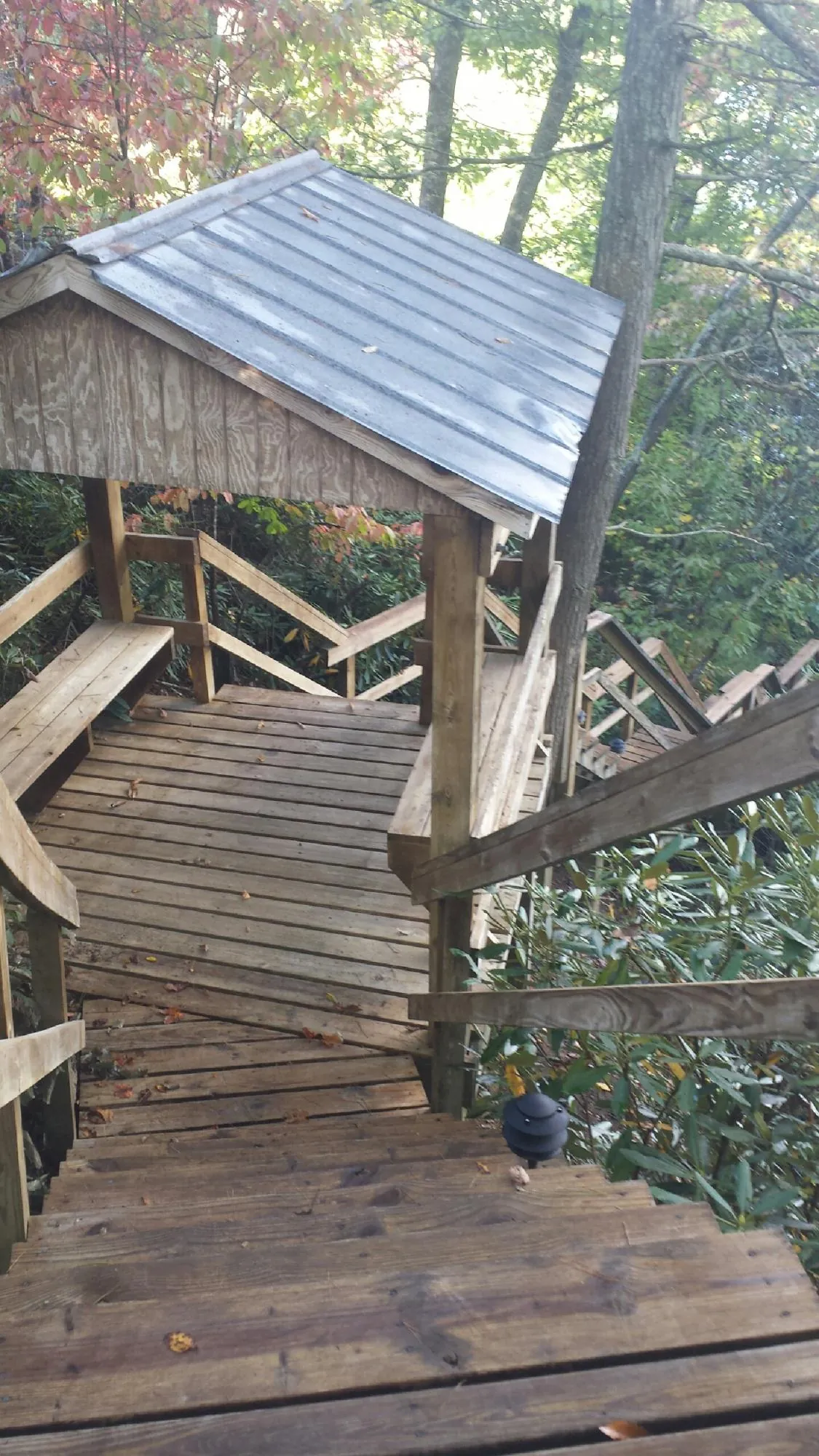 Metal roofed shelter over wooden steps on a wooded walkway — Skylight Repair & Installation work by our crew in Camdenton