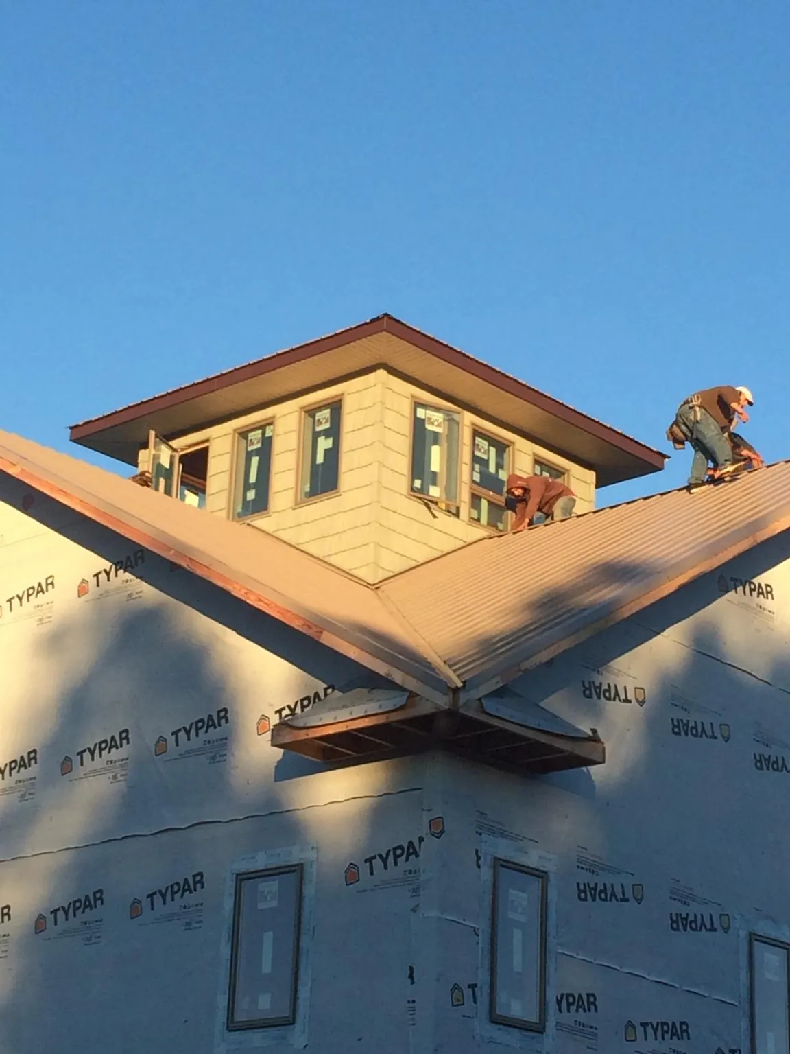 Roofers working around a rooftop cupola on a new metal roof at sunset — Roof Waterproofing in Camdenton by Roofing Brothers